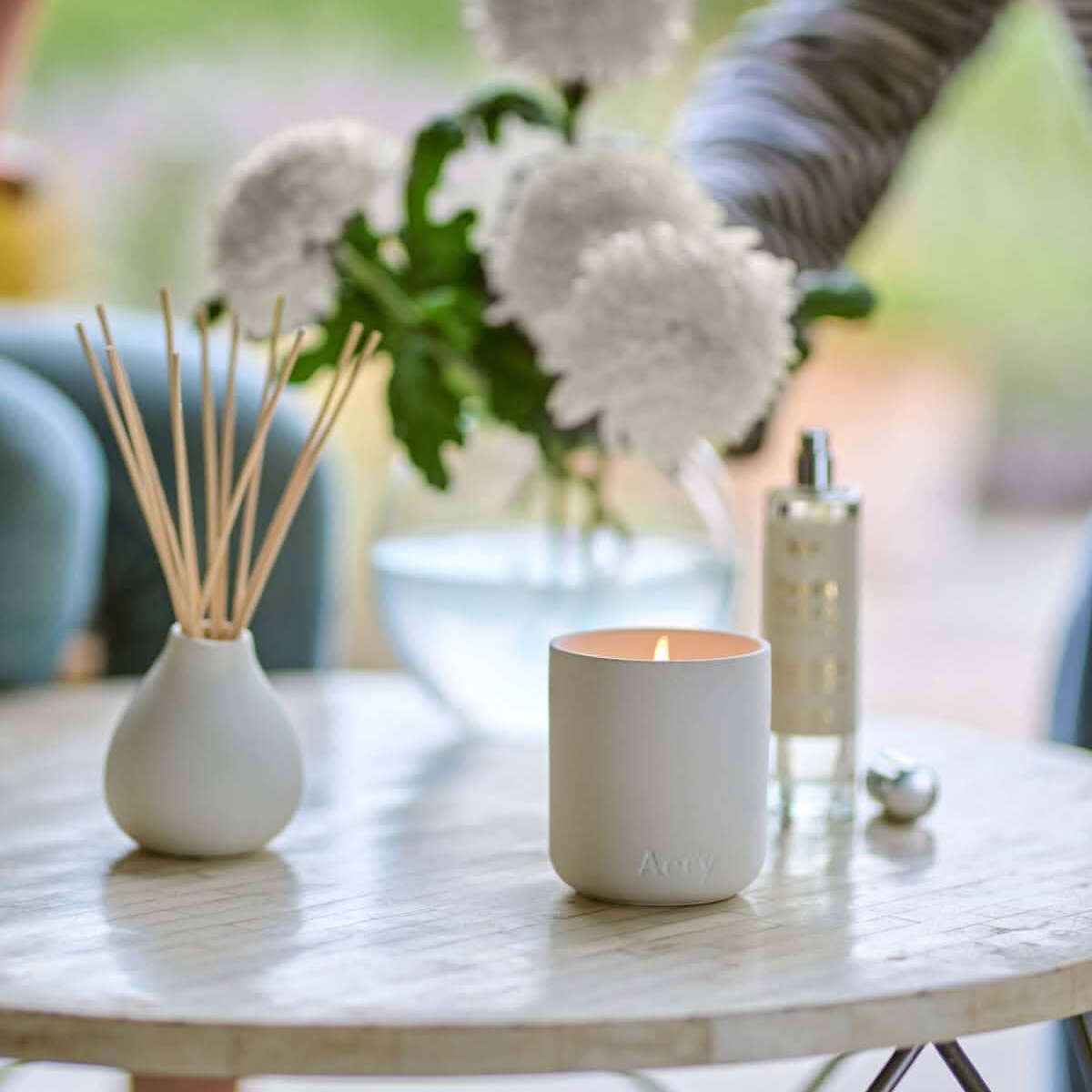 White ceramic Aery candle and diffuser on a table with blurred background